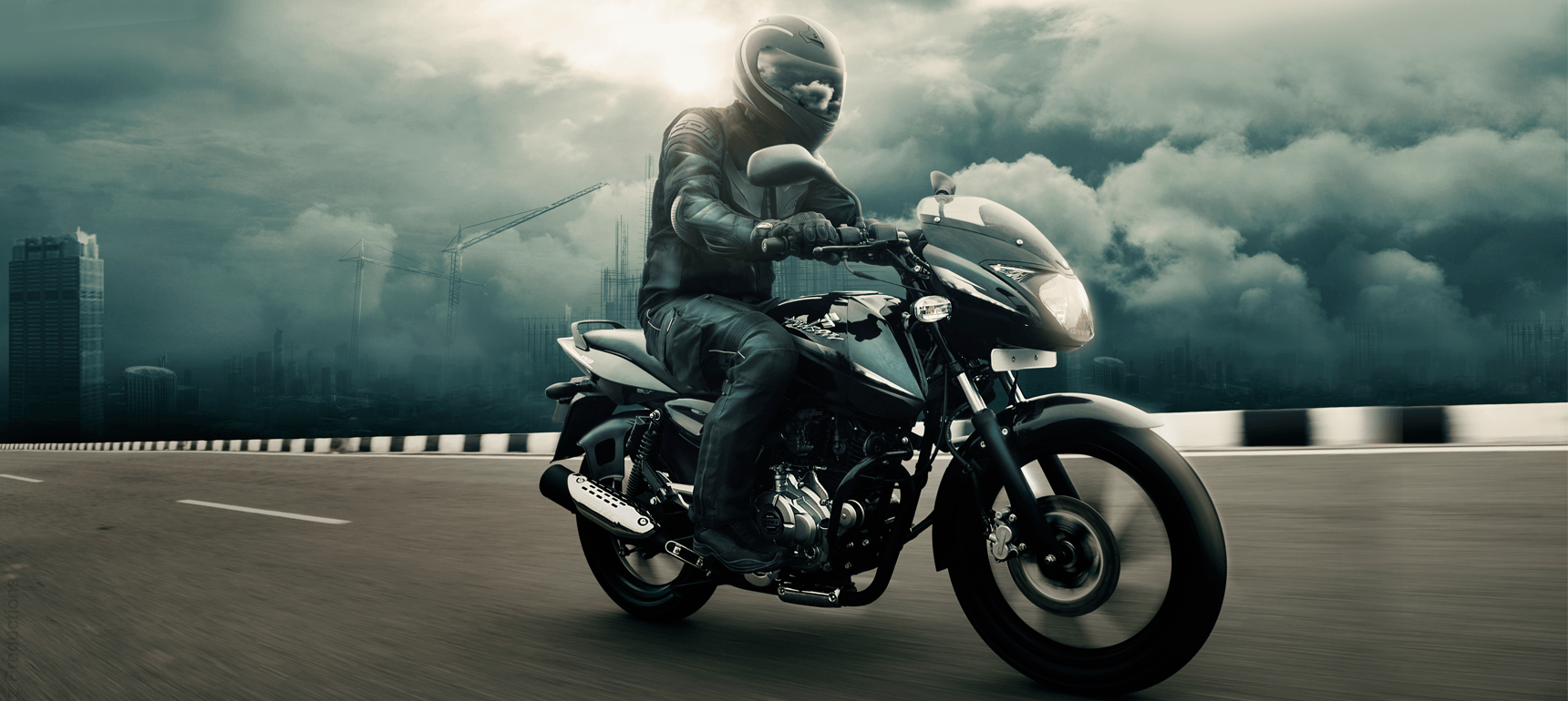 Bajaj Pulsar 150cc Motorcycle for fearless ride 2 A biker is riding black and blue color Bajaj Pulsar 150cc motorcycle wearing black leather jacket and helmet in open road